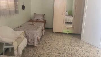 Una camera da letto con un letto, un armadio, una sedia e una porta bianca.