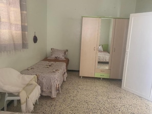 A bedroom with a bed, a wardrobe, a chair, and a white door.