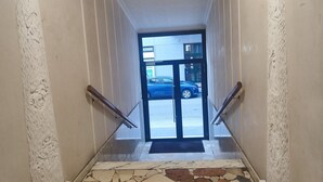 A staircase with white walls and a marble floor leading to a glass door.