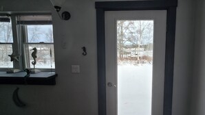 A room with a door leading to a snowy outdoor area, a window with a starfish decoration, and a wall-mounted number '3'.