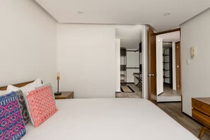 Een moderne hotelkamer met een groot bed, nachtkastjes en een kledingkast.