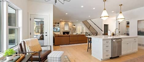 A modern kitchen with a central island, a dining area with a table and chairs, and a staircase leading to a loft.