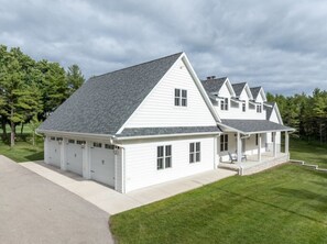 Une maison à deux étages avec un garage, une véranda et une pelouse bien entretenue.
