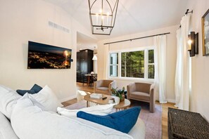 Un salon moderne comprenant un canapé, un fauteuil, une table basse et un tableau représentant un paysage urbain.