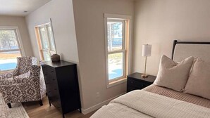 A bedroom with a bed, a desk, a chair, and a window. - Luxury Cottage Escape | 2 King Beds + Fire Pit (Sister Bay)