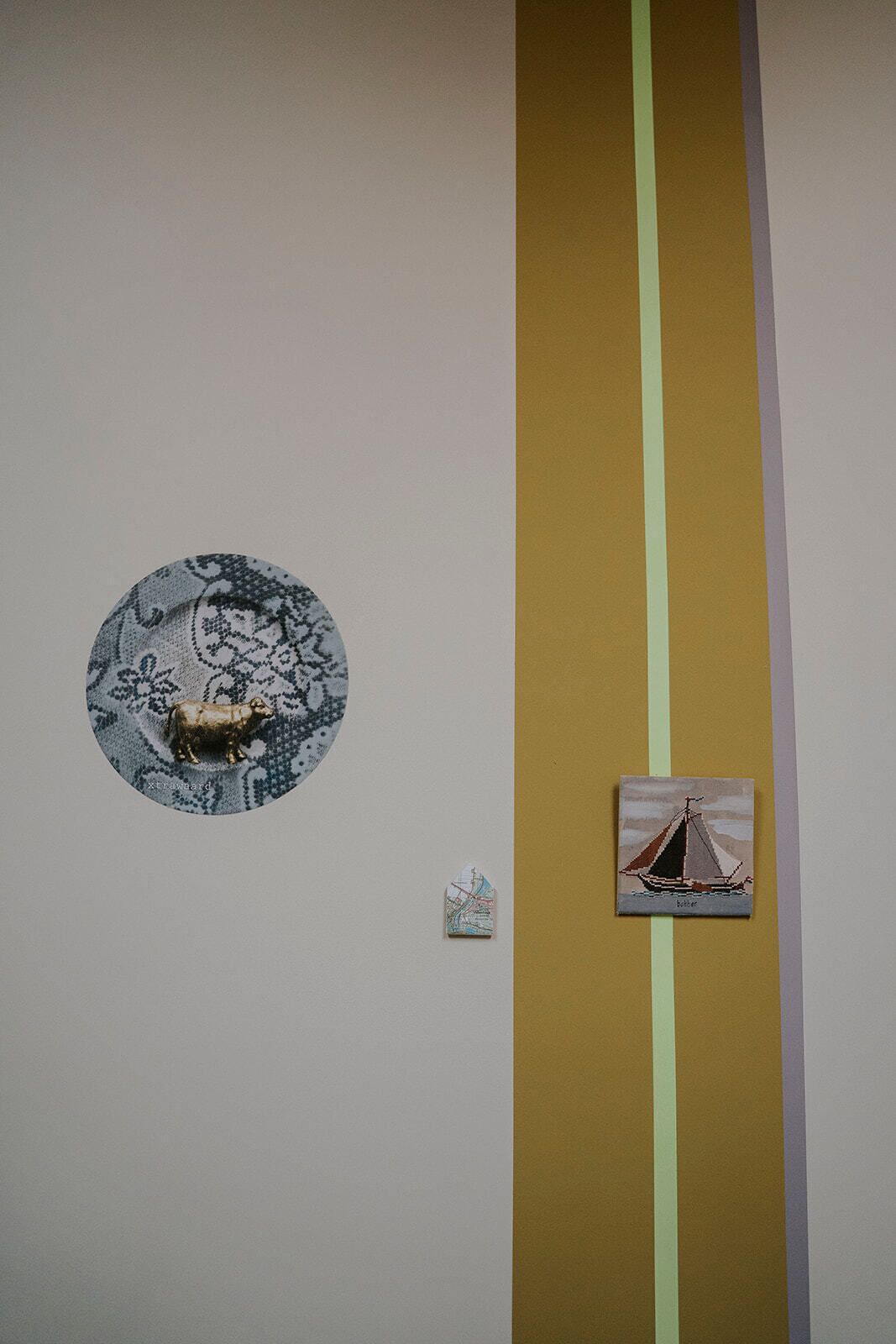 Eine Wand mit einem runden Kunstwerk, das eine Kuh und ein Segelboot zeigt.