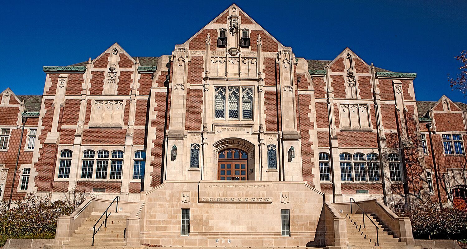 A large, historic building with a prominent entrance, multiple windows, and a central clock tower.