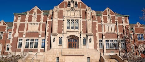 A large, historic building with a prominent entrance, multiple windows, and a central clock tower.
