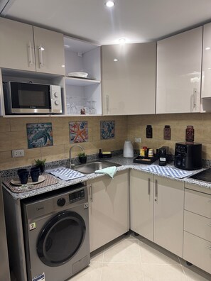 A modern kitchen with a built-in washing machine, a microwave, and a coffee maker. - Sahl Hasheesh Finest Chalet Gravity 5 star beachfront hotel - NON EGYPTIAN ONLY (Hurghada)