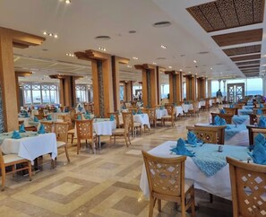 A spacious dining area with multiple tables and chairs, large windows, and a high ceiling with decorative elements. - Sahl Hasheesh Finest Chalet Gravity 5 star beachfront hotel - NON EGYPTIAN ONLY (Hurghada)
