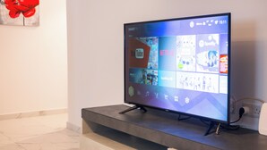 En tv-skärm med platt skärm, placerad på ett stativ, som visar olika streamingtjänster.