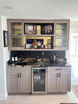 Una cocina moderna con un salpicadero negro y dorado, lavavajillas integrado y una estantería para vinos.