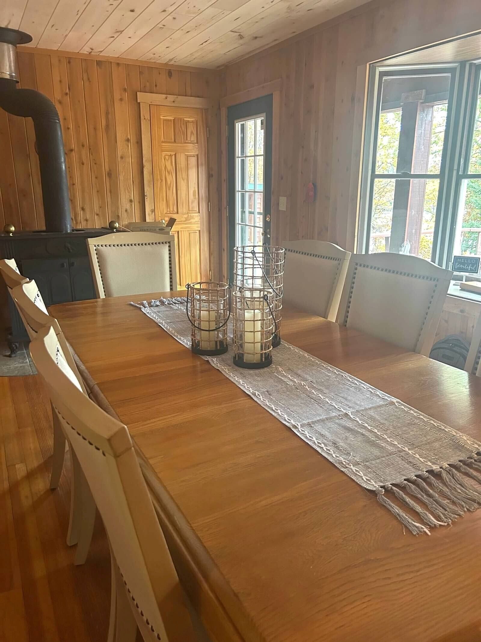 A wooden dining table with chairs, a lace table runner, and candle holders.