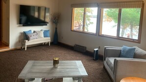 A living room with a white bench, grey sofa, and a coffee table with a vase.