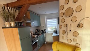 Una cocina con vigas de madera, un sillón amarillo y una pared decorada con rodajas de madera.