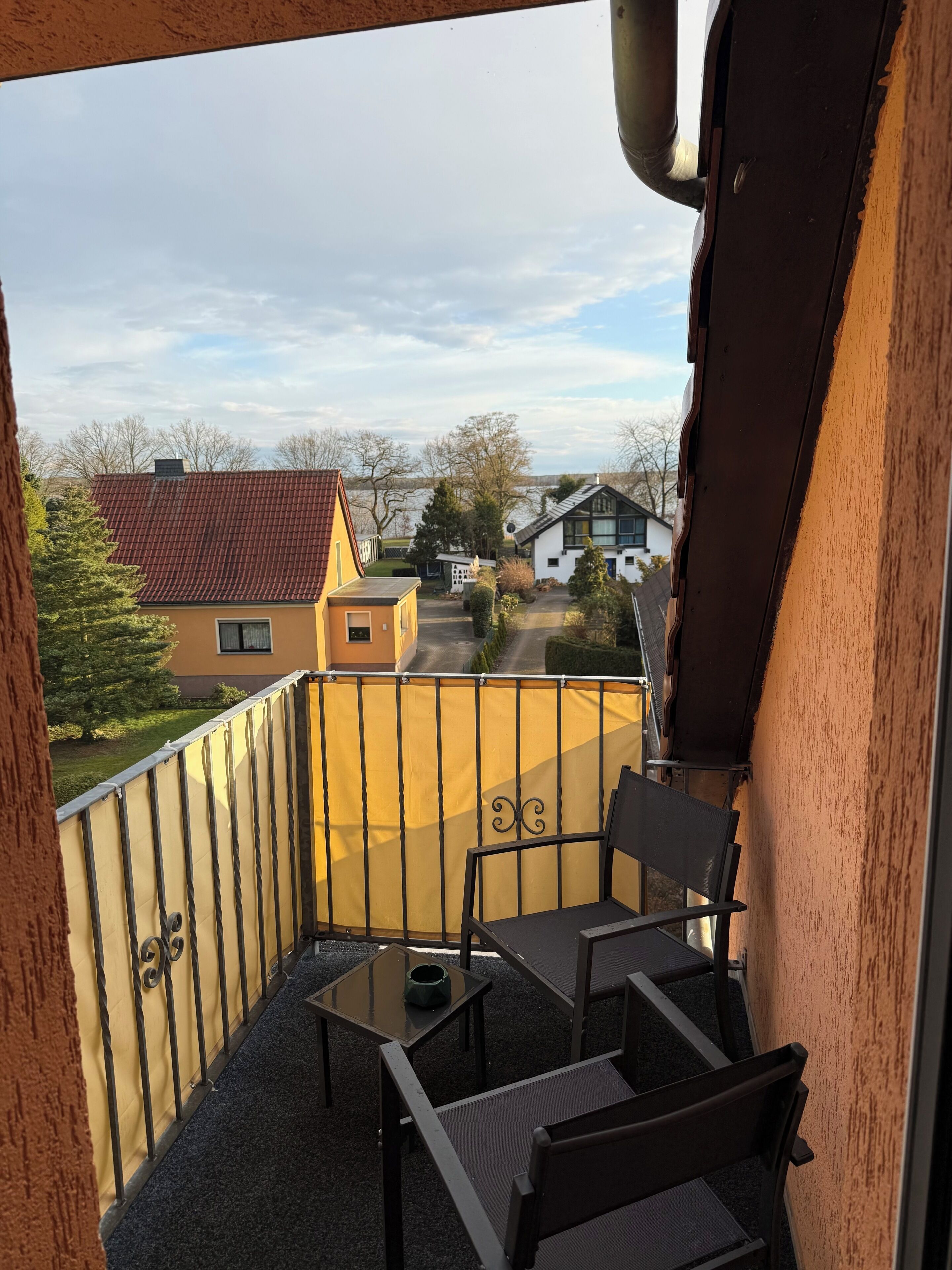 Un balcon donnant sur des maisons, avec une table et deux chaises.