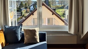 Un dormitorio con un ventanal grande, una cama, un radiador y vistas a una zona residencial.