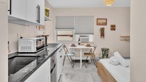 Eine moderne Küche mit weißen Schränken, einer Mikrowelle und einem Essbereich mit Tisch und Stühlen.