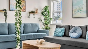 A modern living room with two sofas, a coffee table, and decorative plants. - Santorini Blu | Spacious 2BR Beachfront Suite (Hollywood)