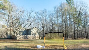 Een voetbaldoel in een tuin, met een huis en bomen op de achtergrond.