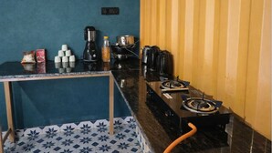 Eine kleine Küche mit Gaskochfeld, Kaffeemaschine und verschiedenen Küchengeräten.