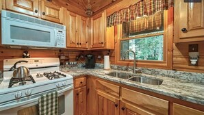 A kitchen with wooden cabinets, a microwave, a stove, and a sink.