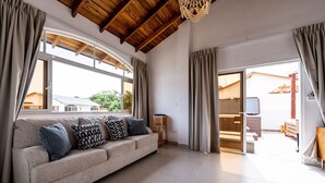 Ein geräumiges Wohnzimmer mit einer Couch, Vorhängen und Blick ins Freie.