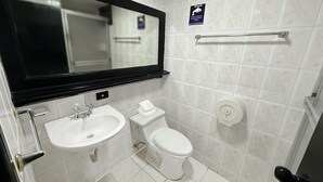 A small, modern bathroom with a white sink, toilet, and mirror. A towel rack is mounted on the wall, and a sign above the toilet advises to flush after use. - HOTEL SANTA MARIA BY LAUZA (Quito)