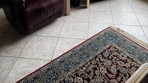 Ein Wohnzimmer mit zwei Ledersesseln, einem kleinen Couchtisch und einem großen Fenster mit Blick auf eine Rasenfläche.
