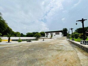 A building with a white facade, a small porch, and a paved area in front. - Malgudi Days and Resorts (Ujjain)