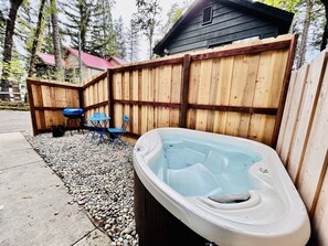 Un jacuzzi en un patio trasero con una valla de madera, un cobertizo y un sendero de grava.