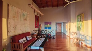 Un vaste espace de vie doté d’un plafond en bois, d’un canapé rouge, d’une table basse et d’œuvres d’art accrochées aux murs.