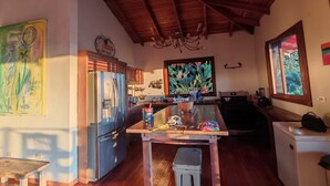 Une cuisine spacieuse avec un plancher en bois, une grande fenêtre et un ventilateur de plafond.