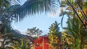 Un espace piscine avec un bâtiment rouge, du mobilier d’extérieur et des palmiers.