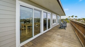 En overdækket terrasse med trægulv, store skydedøre af glas og udendørs møbler.
