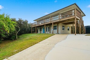 A two-story building with a balcony, a covered porch, and a concrete driveway. - Good Vibrations - Steps to the Beach! (St. Augustine)