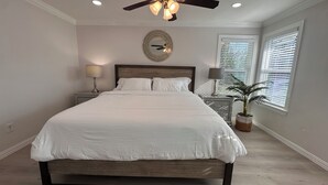 A bedroom with a large bed, a ceiling fan, a mirror, and a window with blinds. - Near AT&T • FIFA & Rangers • Sleeps 8 • Modern Home • Big Yard (Arlington)