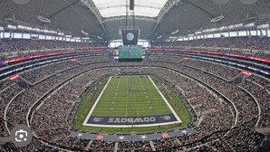 A large indoor stadium with multiple tiers of seating, a central field, and a large screen at the top. - Near AT&T • FIFA & Rangers • Sleeps 8 • Modern Home • Big Yard (Arlington)