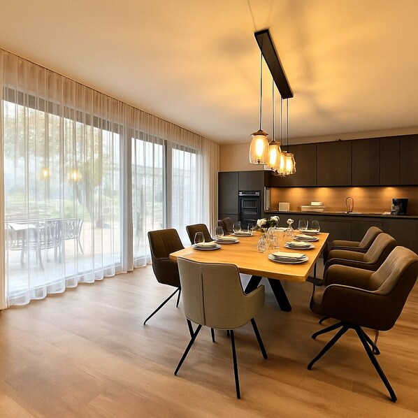 A modern dining area with a wooden table, six chairs, and a kitchen in the background.