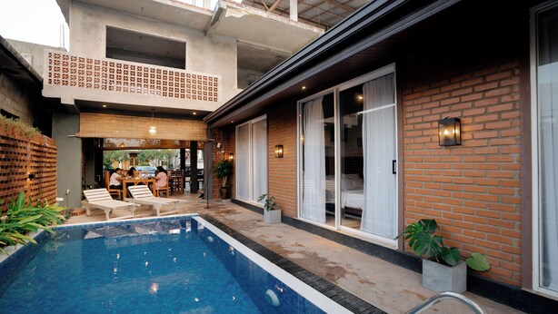 A swimming pool with lounge chairs, a dining area, and a brick exterior wall. - Sunsei Beach Negombo (Negombo)