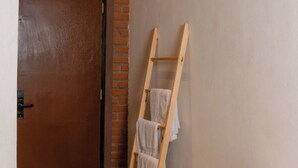 A room with a wooden floor, a brick wall, a wooden ladder leaning against the wall, and a wooden door. - Sunsei Beach Negombo (Negombo)