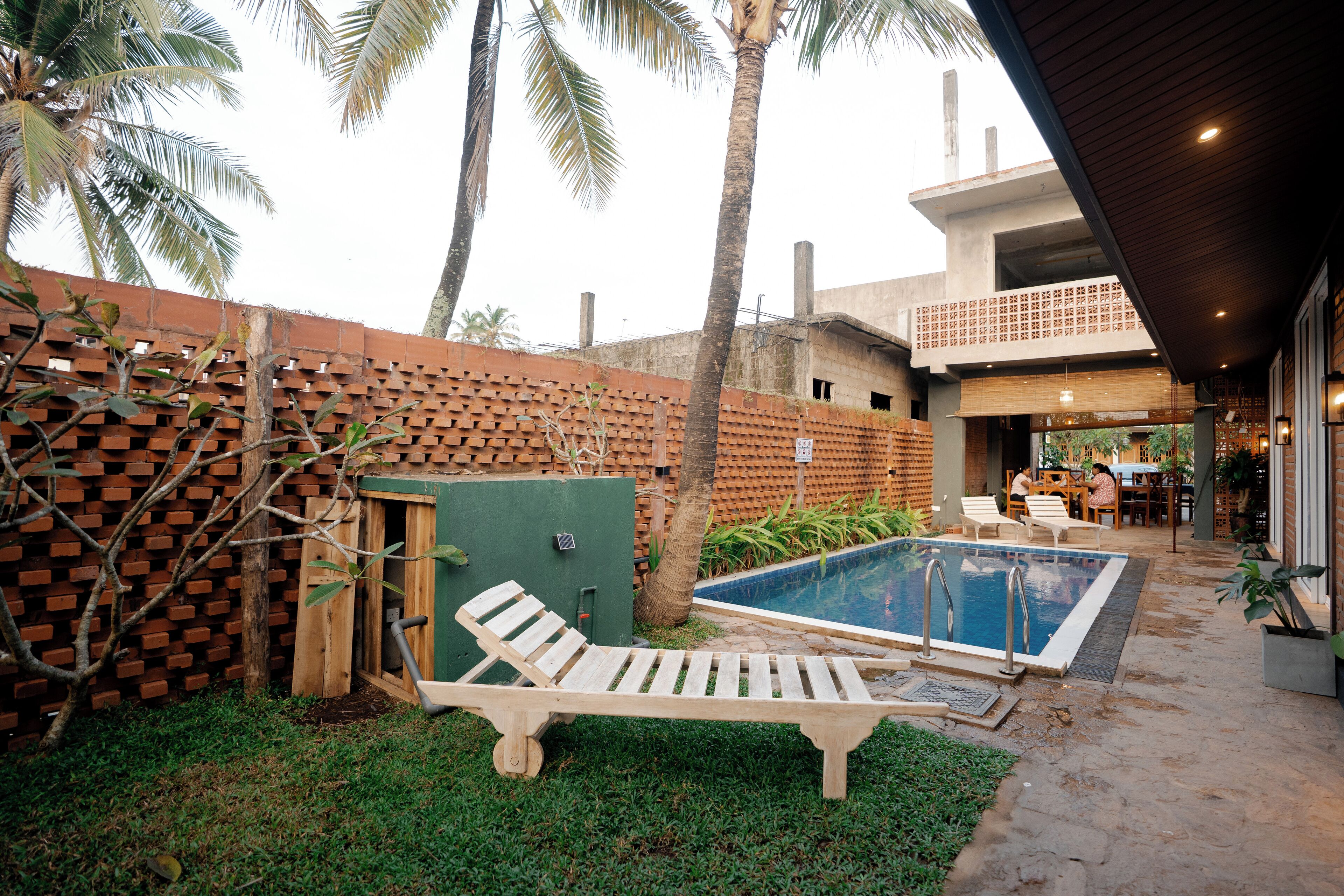 A pool area with a lounge chair, a small pool, and a brick wall.