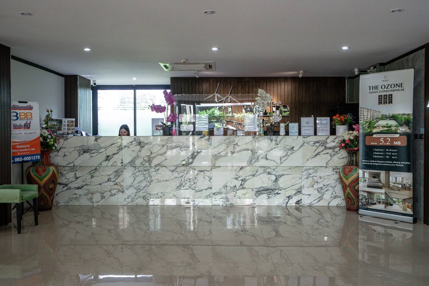 A reception area with a marble counter, a reception desk, and a poster for The Ozone Oasis Condominium.