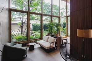 A modern interior with large windows, a sofa, a chair, a table, and a fan. - Suite Azure 2br | Laguna beachside bang tao beach (Choeng Thale)