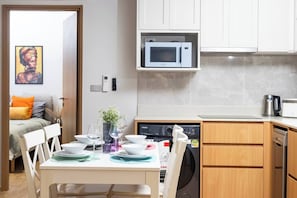 A compact kitchen with a microwave, dishwasher, and a dining area with a table set for two. - Suite Azure 2br | Laguna beachside bang tao beach (Choeng Thale)