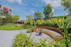 A landscaped outdoor area with a curved seating area, a small table, and various plants. - Suite Eden 2br|garden & Pool|canvas bang tao beach (Choeng Thale)
