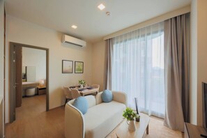 A modern hotel room with a sofa, a dining table, and a TV. - Suite Eden 2br|garden & Pool|canvas bang tao beach (Choeng Thale)