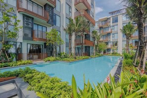 A modern hotel with multiple balconies, a swimming pool, and lush greenery. - Suite Eden 2br|garden & Pool|canvas bang tao beach (Choeng Thale)