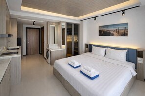 A modern hotel room with a large bed, a built-in wardrobe, a separate bathroom, and a view of the outdoors.