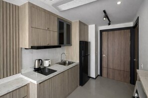 A modern kitchen with wood panel cabinets, a stainless steel sink, a black refrigerator, and a built-in oven.